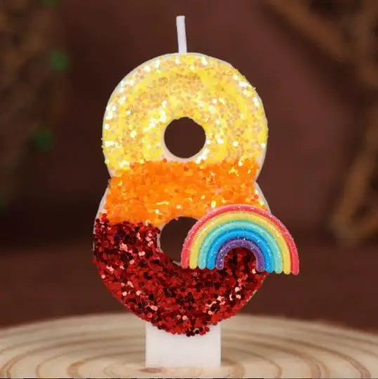 A decorative candle shaped like the number 8 covered in yellow and orange sequins with a rainbow base