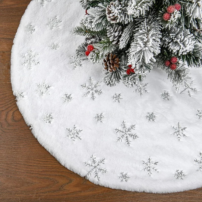 White plush Christmas tree skirt with a snowflake design resting on a wooden surface.