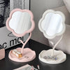 A pink and white makeup mirror set featuring a heart-shaped frame and a stand with decorative jewelry.