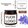 A dark glass jar candle with a custom logo label and blue wind chime decoration.