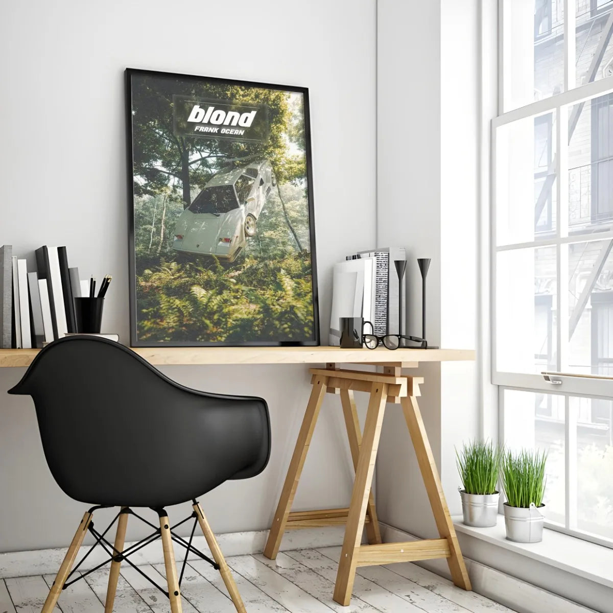 A canvas print of Frank Ocean album art displayed on a wooden desk next to a black chair and window.