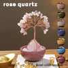 A natural crystal money tree with a rose quartz base displayed on a wooden surface.