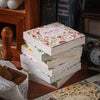 A stack of vintage paper sheets and a wooden stamp are displayed on a dark wooden surface.