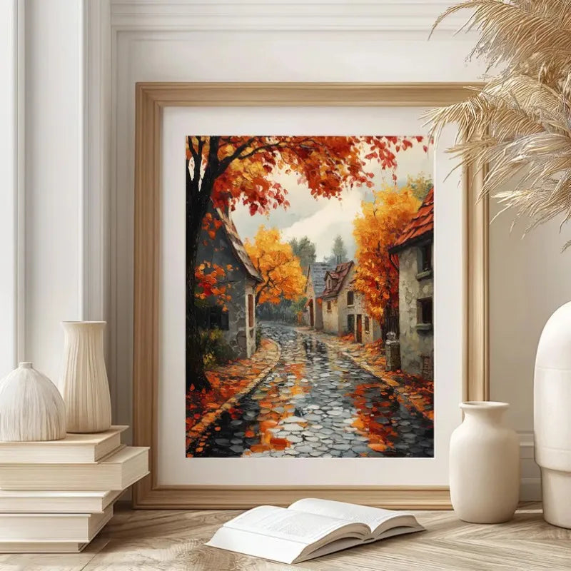 A framed canvas painting depicting an autumn field landscape with vibrant orange and red foliage on a cobblestone path.
