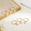 Gold hoop earrings with small cross charms displayed on a wooden surface.