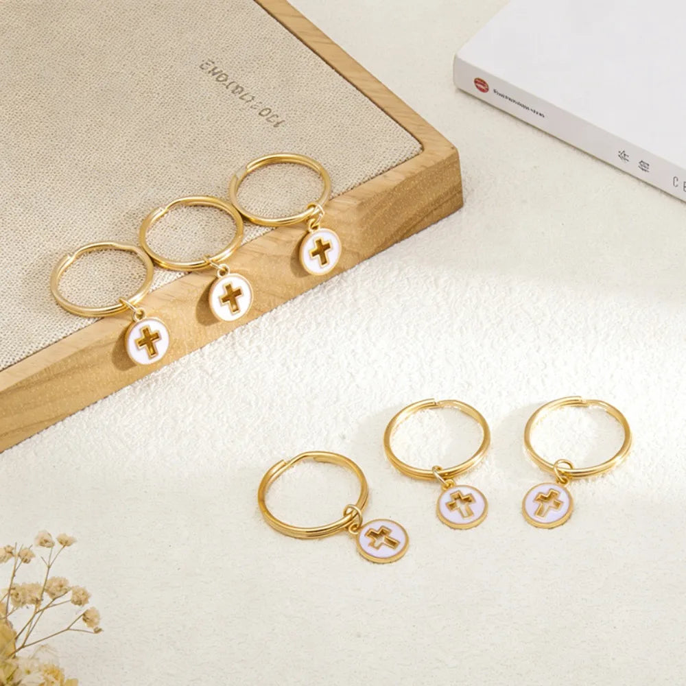 Gold hoop earrings with small cross charms displayed on a wooden surface.