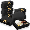 A stack of black kraft paper gift boxes tied with gold ribbon, including a large round box.