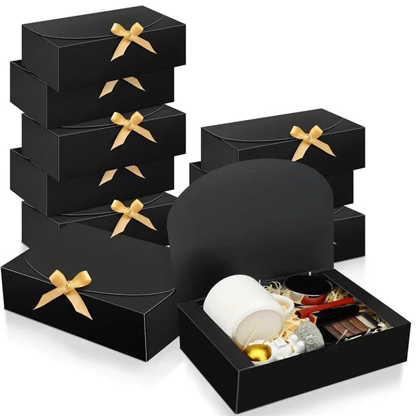 A stack of black kraft paper gift boxes tied with gold ribbon, including a large round box.