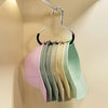 A rack of colorful circle ring hats hanging on a metal hanger against a light wall.