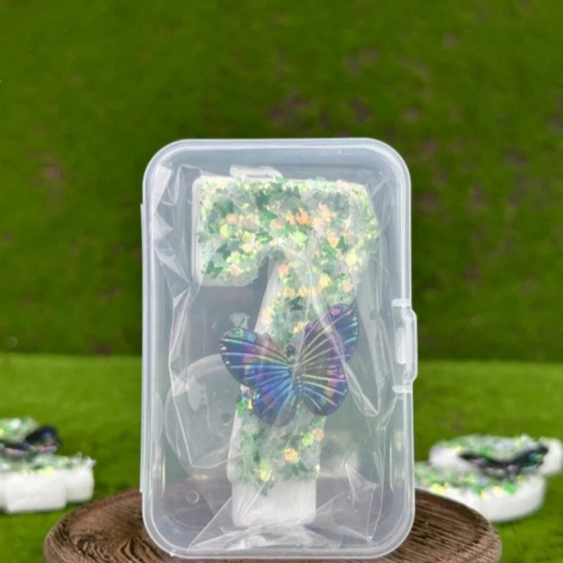 Clear plastic container holding green sequin butterfly number candles for birthday cakes