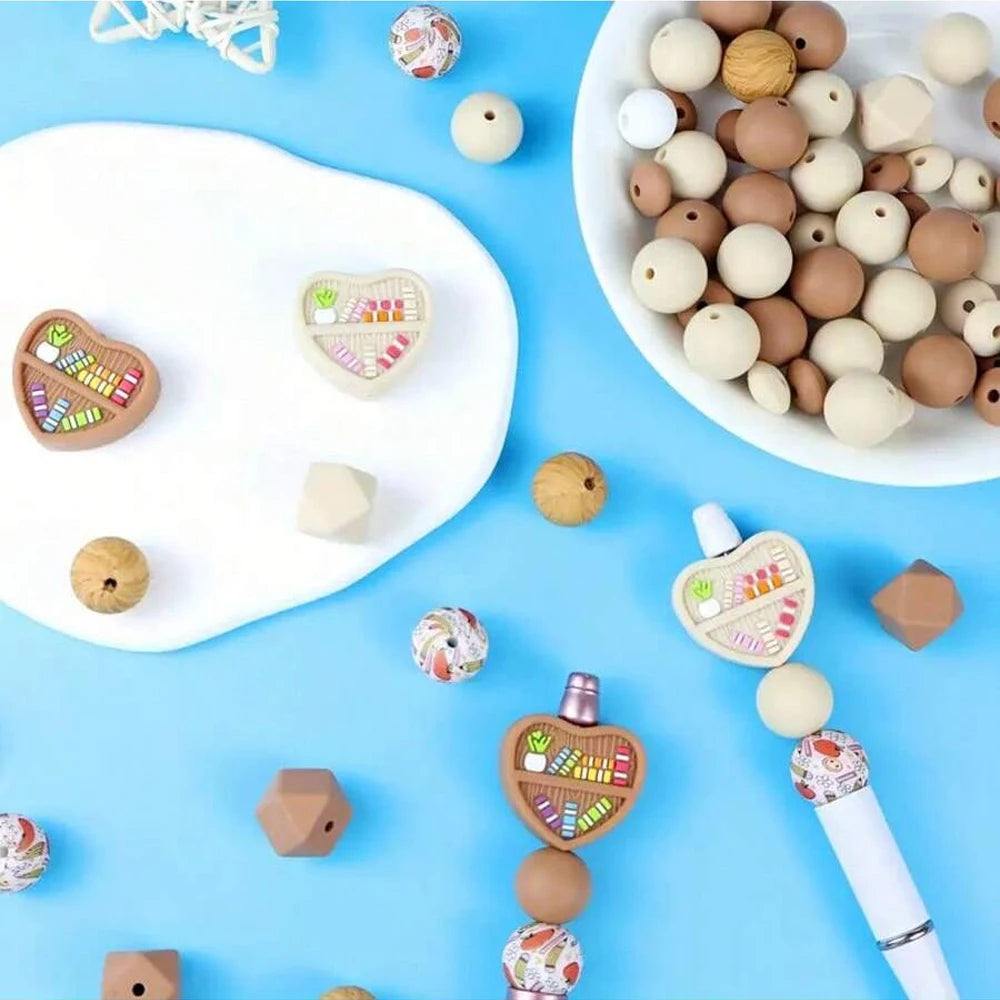 A collection of round silicone beads in various natural and pastel colors arranged on a white plate and blue background.