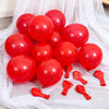 A collection of glossy red latex balloons scattered on white sheer fabric.