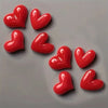 A set of red heart-shaped fridge magnets arranged on a gray surface.