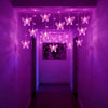 String lights shaped like pink and white butterflies hang in a purple hallway.