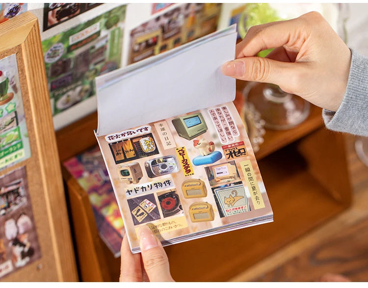 A hand holds up a pack of retro cartoon PET die cut stickers for scrapbooking and journaling.