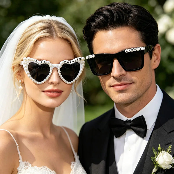 A bride and groom posing outdoors wearing pearl decorated sunglasses for wedding photos.