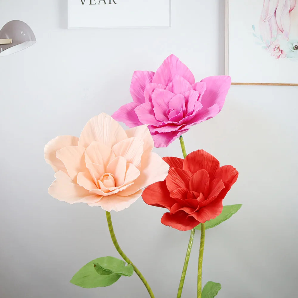 A display of three large, vibrant pink and coral foam rose flowers on green stems.