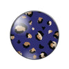 A round glass cabochon with a dark blue background featuring irregular leopard print spots in black and tan.
