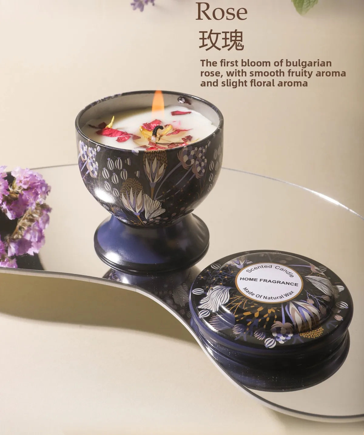 A dark ceramic bowl filled with wax and a rose-themed candle is displayed on a silver tray.