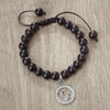 A black beaded bracelet with a silver charm featuring the zodiac sign Virgo.