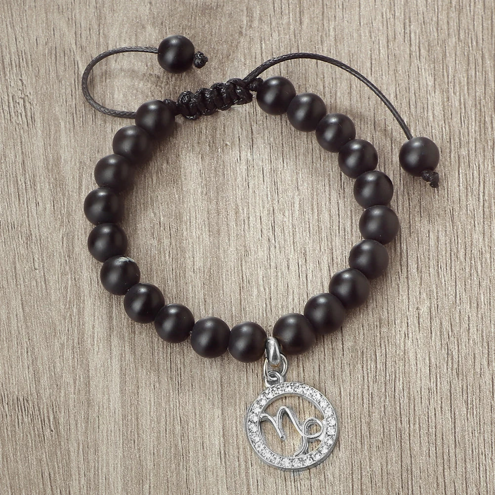 A black beaded bracelet with a silver charm featuring the zodiac sign Virgo.