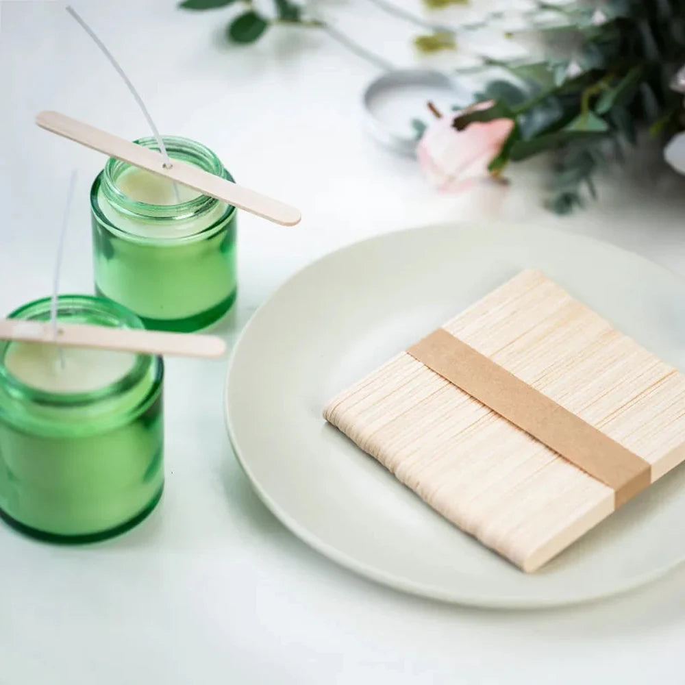 Green soy wax candles in glass jars with wooden wicks on a white plate
