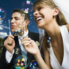 A smiling bride and groom holding heart-shaped bubble wands during a celebration.