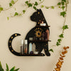 A black cat silhouette decoratively mounted on a floating shelf, featuring crystals and a lit candle, surrounded by green vin
