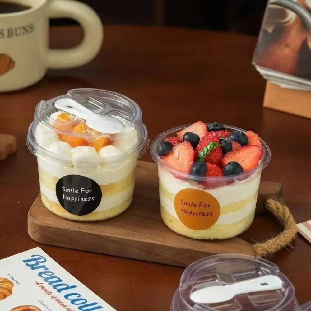 A wooden tray holds two clear pudding cups with lids and spoons, labeled Smile For Happiness.