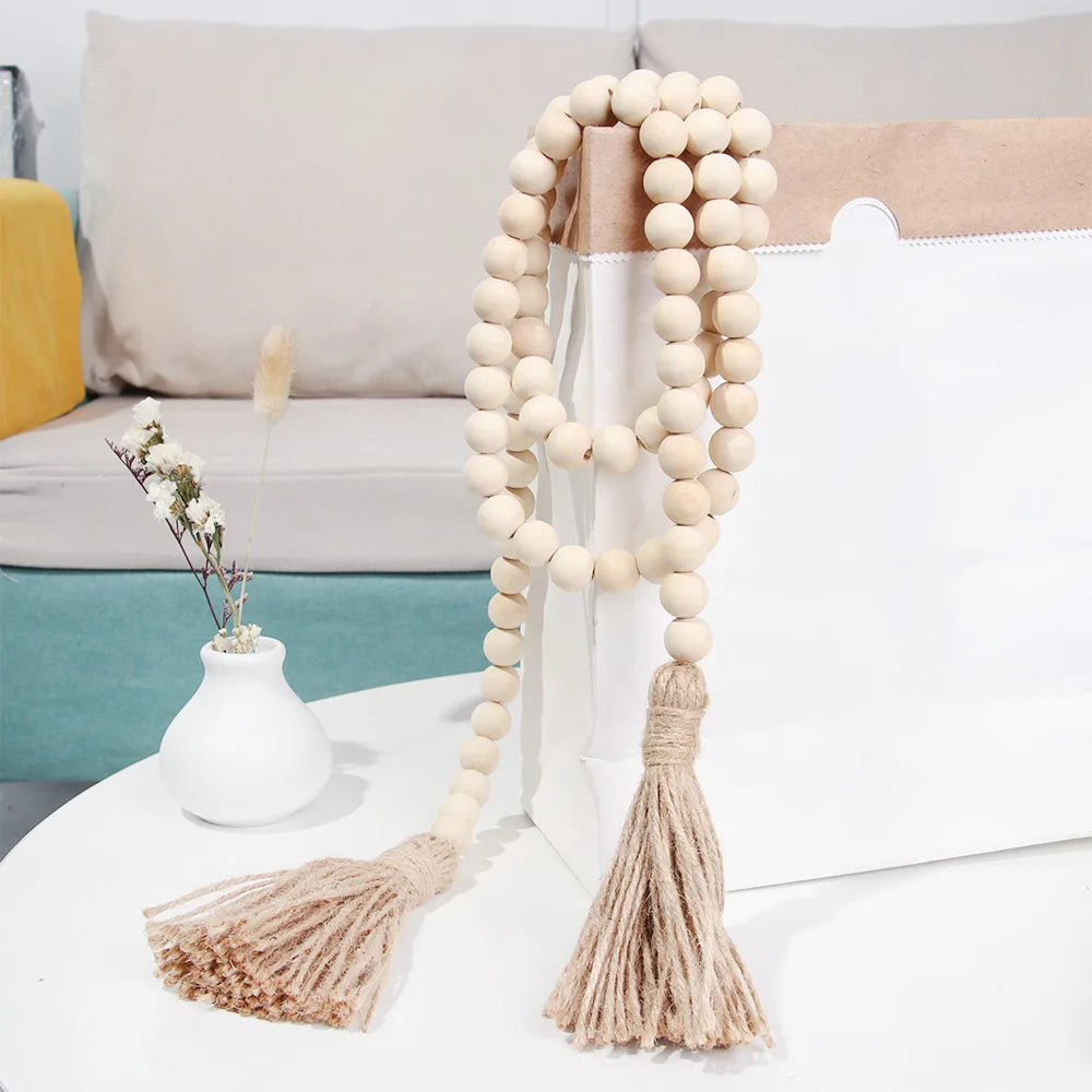 A handmade wood and jute bead garland with a tassel displayed on a white surface.