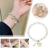 A close-up of a natural stone lily of the valley bracelet worn on a wrist, featuring white and gold beads.