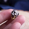 A hand holds a silver skull bead pendant necklace with a gold movable jaw detail.