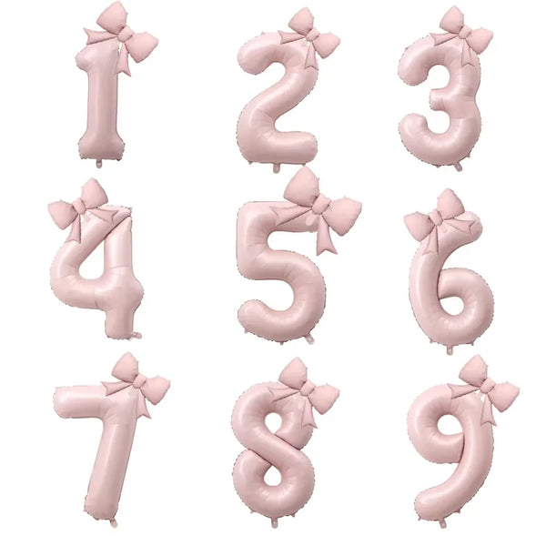 A set of large pink foil number balloons from 0 to 9, each decorated with a bow.