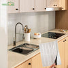 A kitchen countertop with a stainless steel faucet and sink, featuring self-adhesive heat resistant wall tiles.
