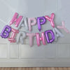 A garland of 13 foil letter balloons spelling out HAPPY BIRTHDAY in various shades of pink and purple