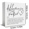A white wooden sign with black script that reads difference maker.