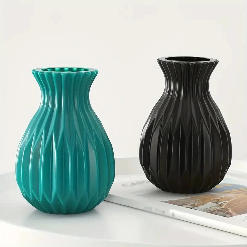 A pair of Nordic style ceramic flower vases, one teal and one black, displayed on a white surface.
