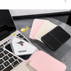 A pink portable folding HD makeup mirror is shown resting on a laptop keyboard with a yellow charm.