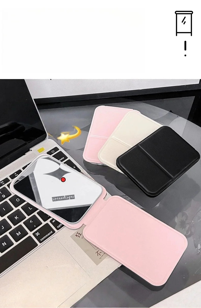 A pink portable folding HD makeup mirror is shown resting on a laptop keyboard with a yellow charm.