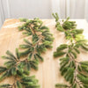 A branch of artificial green pine garland lying on a light wooden surface.