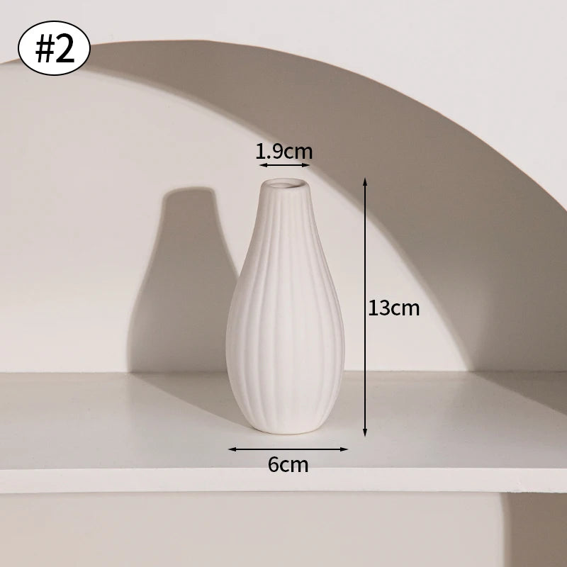 A white ceramic bud vase with a ribbed texture is displayed on a shelf.