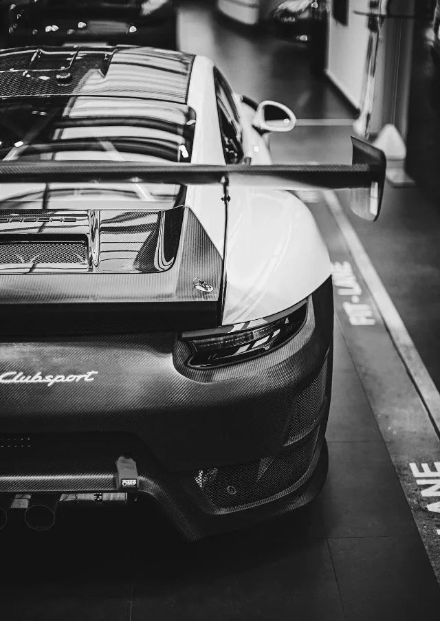 Gros plan en noir et blanc sur la calandre et le capot d'une voiture de sport moderne avec des accents en fibre de carbone.