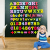 A young child sits in front of a chalkboard covered with colorful magnetic letters and numbers.