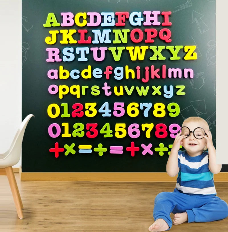 A young child sits in front of a chalkboard covered with colorful magnetic letters and numbers.