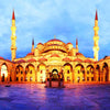A large, golden-yellow Islamic mosque with domes and minarets under a blue sky.