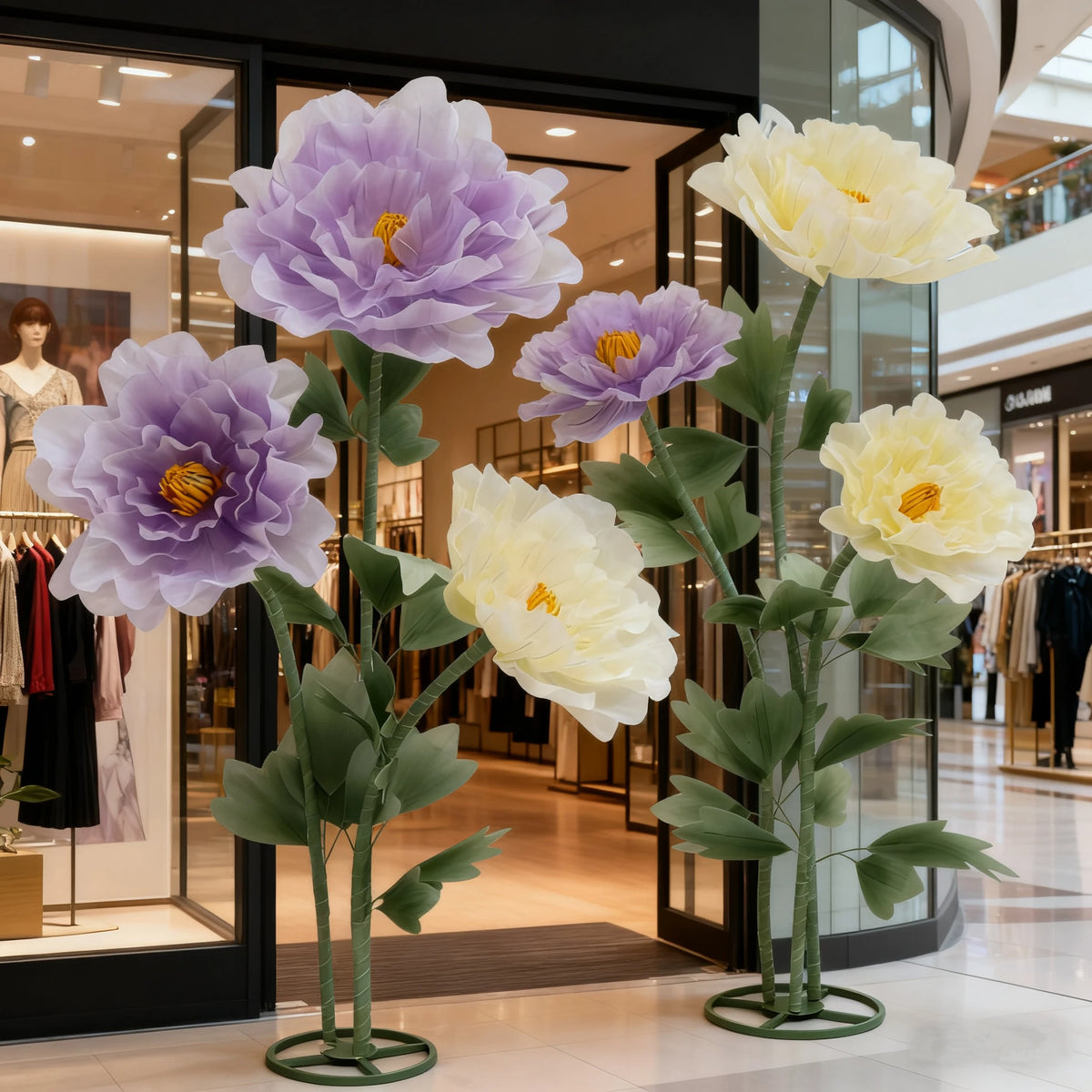 Large artificial silk purple and yellow poppy flowers displayed on a stand in a retail setting.