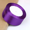 A roll of vibrant purple satin ribbon used for crafts and gift wrapping.