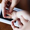 A hand is pressing a baby's hand onto a photo frame to create a handprint memory.