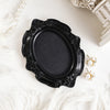 Black ornate oval frame for wall decor resting on white fluffy fabric