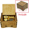 A wooden music box featuring a gold-colored mechanism and decorative patterns, with an engraved design on the lid.